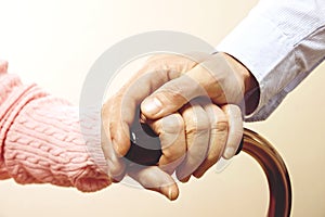 Mature female in elderly care facility gets help from hospital personnel nurse. Close up of aged wrinkled hands of senior woman. G