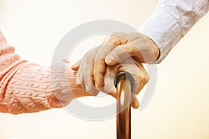 Mature female in elderly care facility gets help from hospital personnel nurse. Close up of aged wrinkled hands of senior woman. G