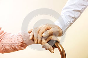 Mature female in elderly care facility gets help from hospital personnel nurse. Close up of aged wrinkled hands of senior woman. G