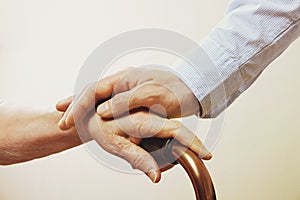 Mature female in elderly care facility gets help from hospital personnel nurse. Close up of aged wrinkled hands of senior woman. G