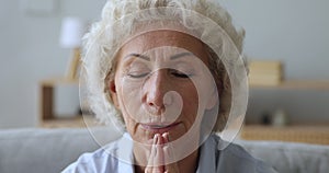 Senior elderly woman praying with hope at home, closeup view