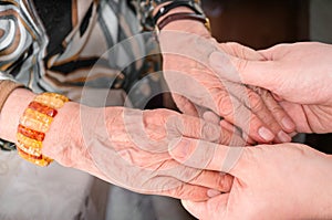 Senior or eldery assistance concept. Young man holds hands of senior woman