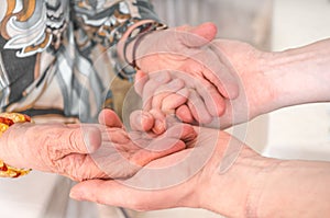 Senior or eldery assistance concept. Young man holds hands of senior woman photo