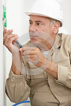 senior electrician using screwdriver on wall socket