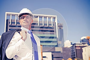 Senior elegant builder man in suit at construction site on sunny