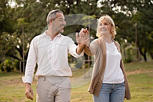 Senior elegant caucasian couple dancing looking at each other feeling love and cherish on their anniversary in the park with copy