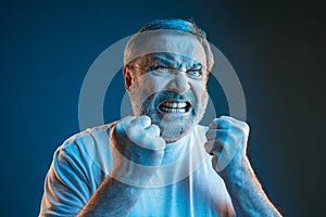 The senior emotional angry man screaming on blue studio background