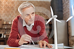 Senior engineer measuring distance and looking at wind turbine