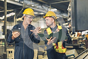 senior engineer talking explain machine working process for teaching training young male worker at heavy industry factory
