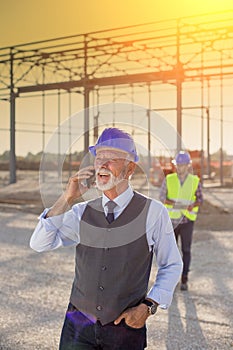 Senior engineer talking on phone at building site