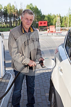 Senior European man filling own car with gasoline in gas stations