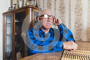 senior European man sitting at the table and thinking about memories medium closeup indoor seniority concept