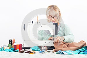 Senior European woman focused on sewing, using sewing machine at home