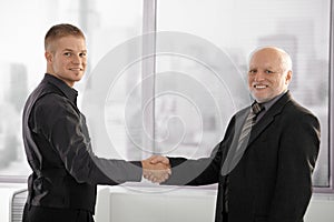 Senior executive shaking hands with young employee