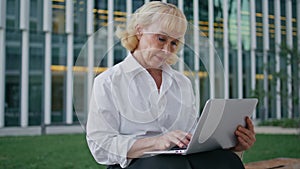 Senior executive working online at wireless computer outdoors. Pensioner typing