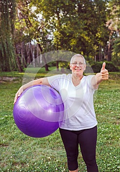Senior exercise - thumb up for healthy exercising woman with fitness balls in park