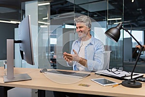 Senior and experienced employee, advises the buyer on a video call, the man works in a modern office uses a headset