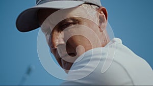 Senior face looking golf ball on sunny blue sky. Old man play sport game outside