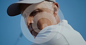 Senior face looking golf ball on sunny blue sky. Old man play sport game outside