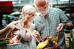 Senior family couple choosing bio food fruit and vegetable on the market during weekly shopping