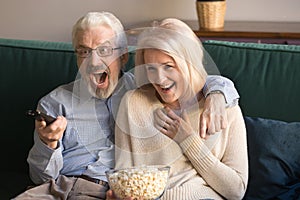 Senior family couple sport fans watching football on tv.
