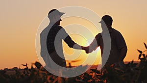 Senior farmer shakes hands with a young colleague. Smile, positive emotions