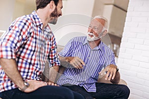 Senior Father With Adult Son Relaxing On Sofa