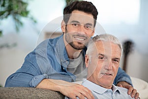 senior father with adult son relaxing on sofa at home