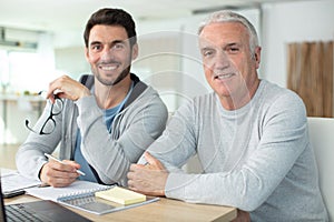 senior father with adult son relaxing on sofa at home