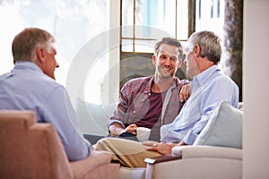 Senior Father With Adult Son Relaxing On Sofa At Home