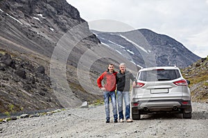 Senior father and adult son traveling together by car in mountains, off road driving on dirt road