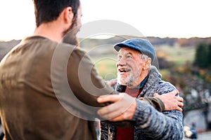 Senior father and his son on walk in nature, talking.