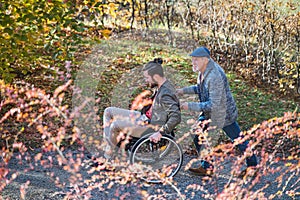 Senior father and his son in wheelchair on walk in nature.