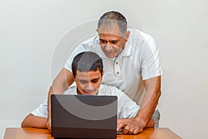 Happy family old grandfather and grandson on laptop.Elderly teacher trainer and teen pupil boy.