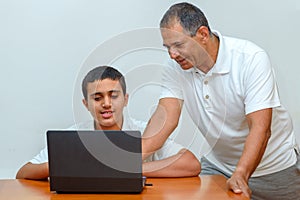 Happy family old grandfather and grandson on laptop.Elderly teacher trainer and teen pupil boy.