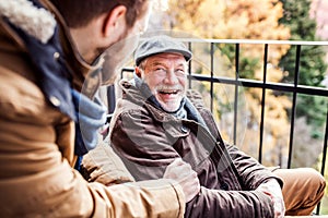 Senior father in wheelchair and young son on a walk.