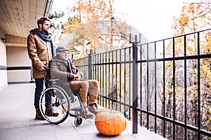 Senior father in wheelchair and young son on a walk.