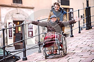 Senior father in wheelchair and young son on a walk.