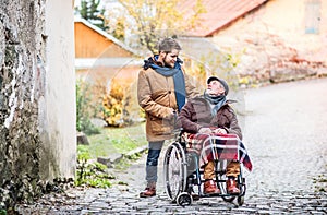 Senior father in wheelchair and young son on a walk.