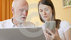 Senior father and young daughter using smartphone. Teen teaching grandfather how to use cellphone