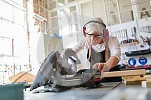 Senior female carpenter working with a circular saw