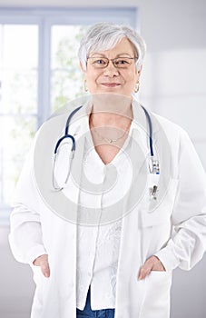 Senior female doctor smiling at hospital corridor