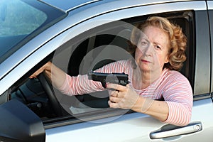 Senior female driver holding a gun