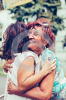 Senior female friends hugging, happy to see each other after many years