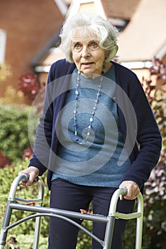 Senior Female In Garden Using Walking Frame