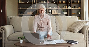 Senior female manage finances at home office using laptop calculator