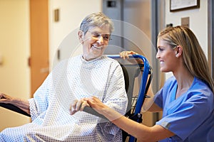 Senior Female Patient Being Pushed In Wheelchair By Nurse