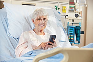 Senior Female Patient In Hospital Bed Using Mobile Phone