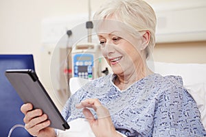 Senior Female Patient Using Digital Tablet In Hospital Bed