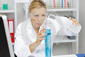 senior female scientist adding liquid to large vial photo